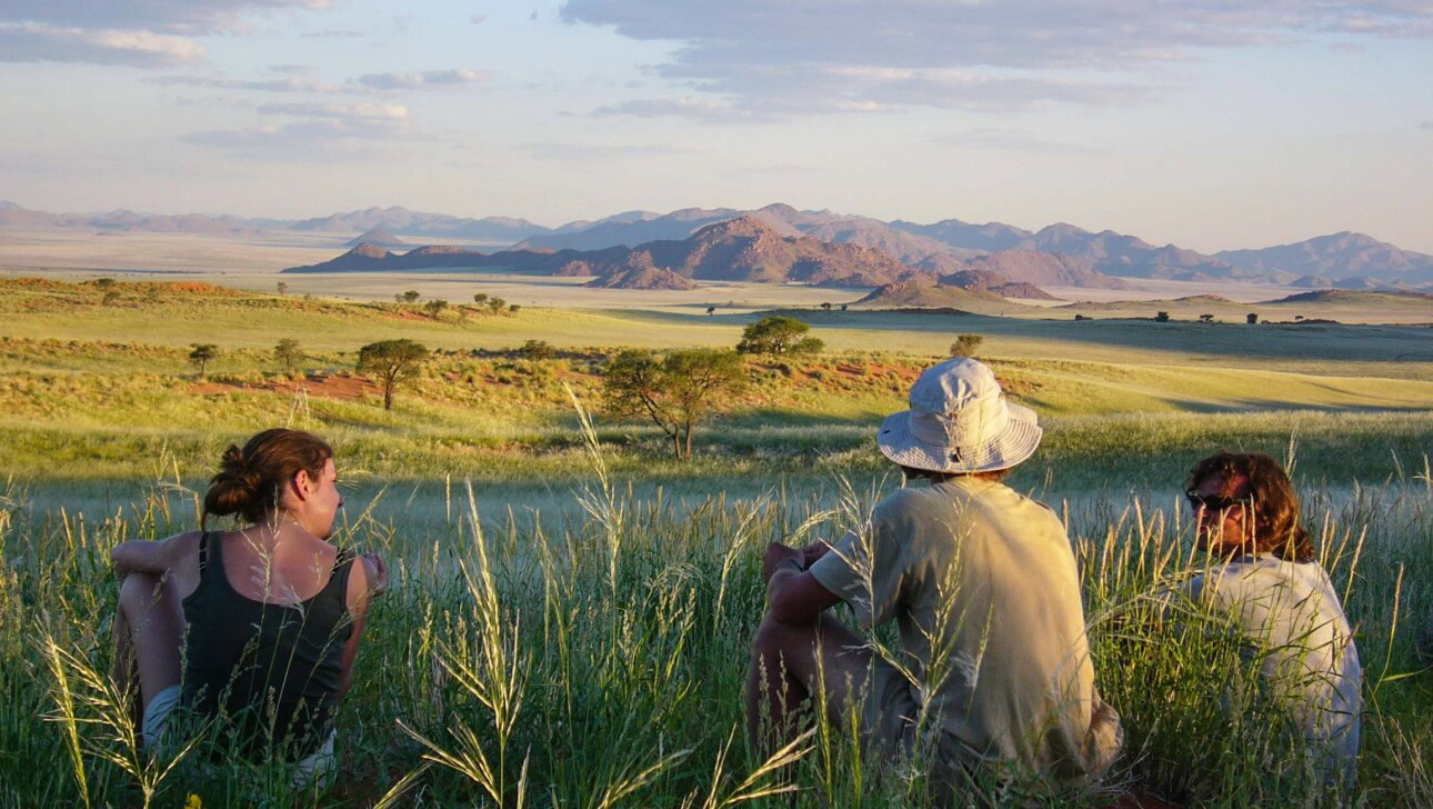 People sitting on a hill on a trail in Namibia.