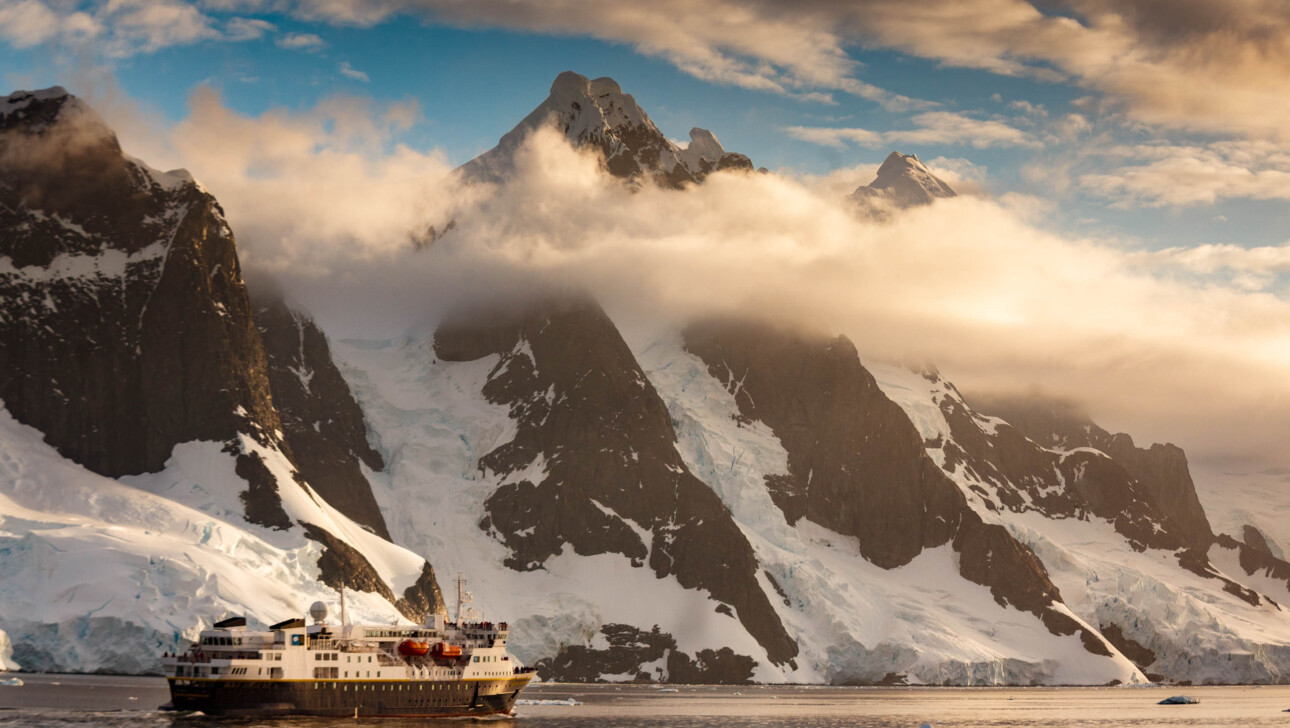 An expedition ship cruises along the Lemaire Channel, Antarctica.